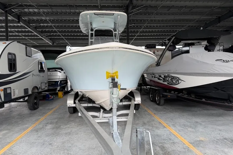 Slide: The Image of 2024 Key West 219 FS boat on trailer, parked in covered storage between RVs. - 4