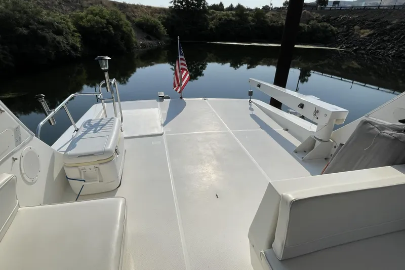 Slide: The Image of 2008 Meridian 490 Pilothouse boat deck with seating, American flag, and calm water backdrop. - 44