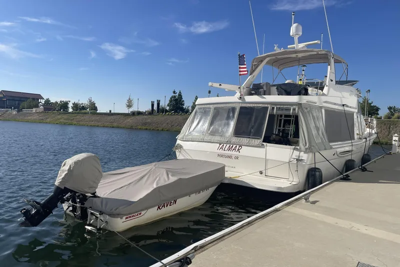 Slide: The Image of 2008 Meridian 490 Pilothouse yacht docked with covered dinghy, clear sky background. - 49
