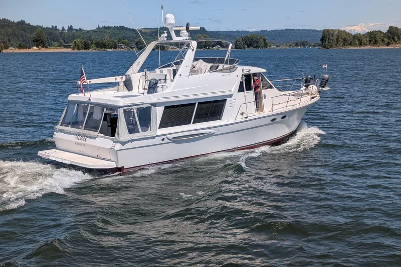 Slide: The Image of 2008 Meridian 490 Pilothouse yacht cruising on a scenic lake with forested hills. - 58