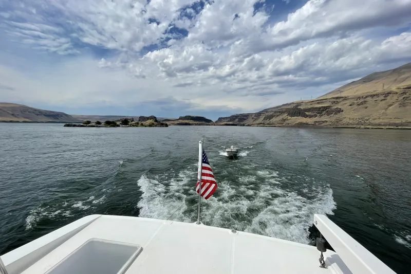 Slide: The Image of 2008 Meridian 490 Pilothouse cruising on a scenic river with American flag, under a cloudy sky. - 64
