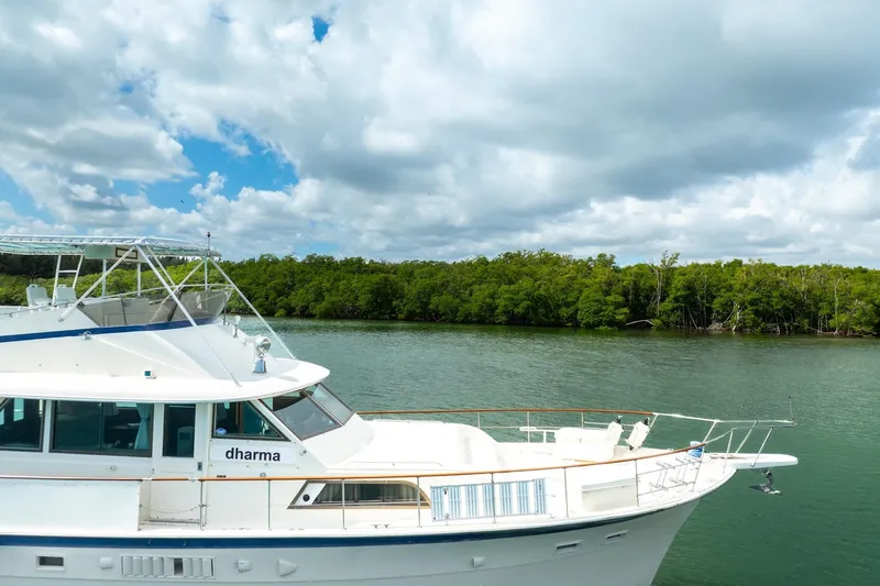 Slide: The Image of 1978 Hatteras 53 Yacht Fisherman on serene water with lush green backdrop. - 14