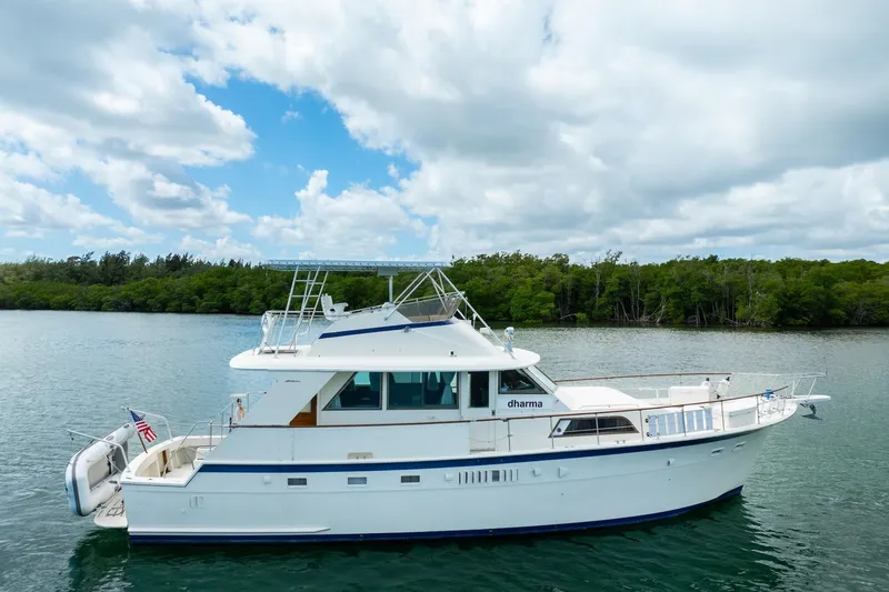 Slide: The Image of 1978 Hatteras 53 Yacht Fisherman on serene water, under a partly cloudy sky. - 7