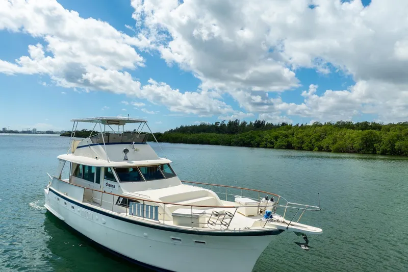 Slide: The Image of 1978 Hatteras 53 Yacht Fisherman cruising on a serene lake under a partly cloudy sky. - 8