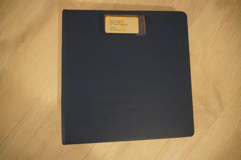 Slide: The Image of Dark blue binder on wooden floor, labeled "Hatteras 53 Yacht Fisherman 1978." - 87