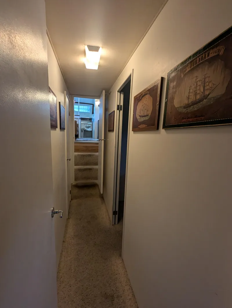 Slide: The Image of Narrow hallway inside a 1965 Pacemaker 53 Motor Yacht, featuring nautical-themed wall art. - 14