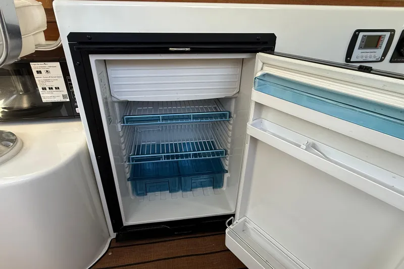 Slide: The Image of Compact refrigerator inside 2023 Rosborough 246 Halifax boat, featuring blue shelves and open door. - 17
