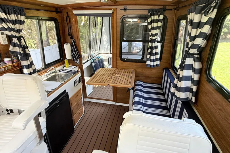 Slide: The Image of 2023 Rosborough 246 Halifax interior with striped curtains, seating, and compact kitchen area. - 12