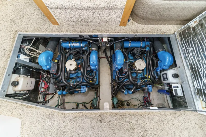 Slide: The Image of Engine compartment of a 1996 Cruisers Yachts 3650 Aft Cabin, showcasing dual blue engines. - 50