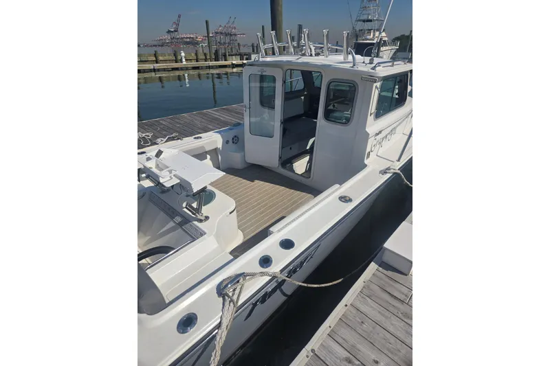 Slide: The Image of 2022 Parker 2120 Sport Cabin boat docked, showcasing spacious deck and cabin area. - 8
