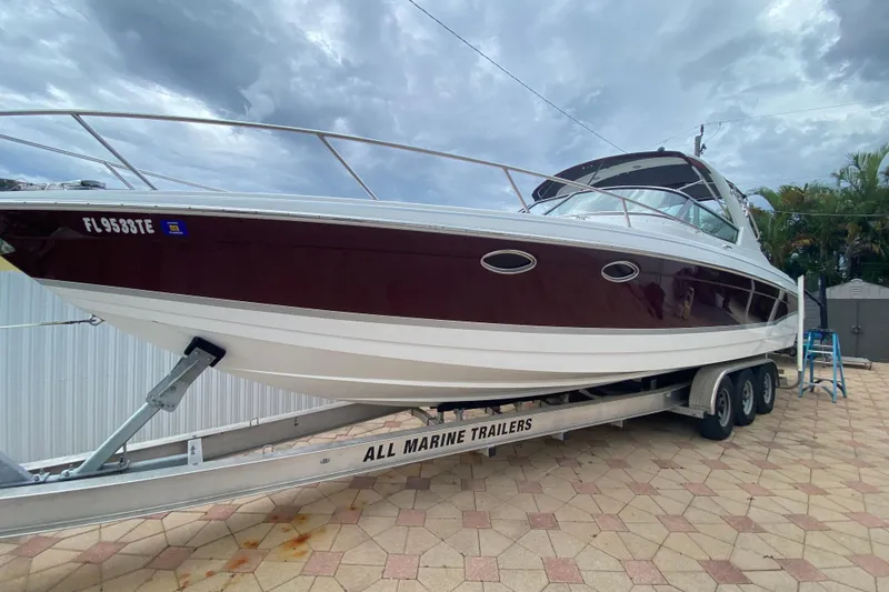 The Image of 2009 Formula 330 Sun Sport boat on trailer, parked on a paved surface under cloudy skies. - 0