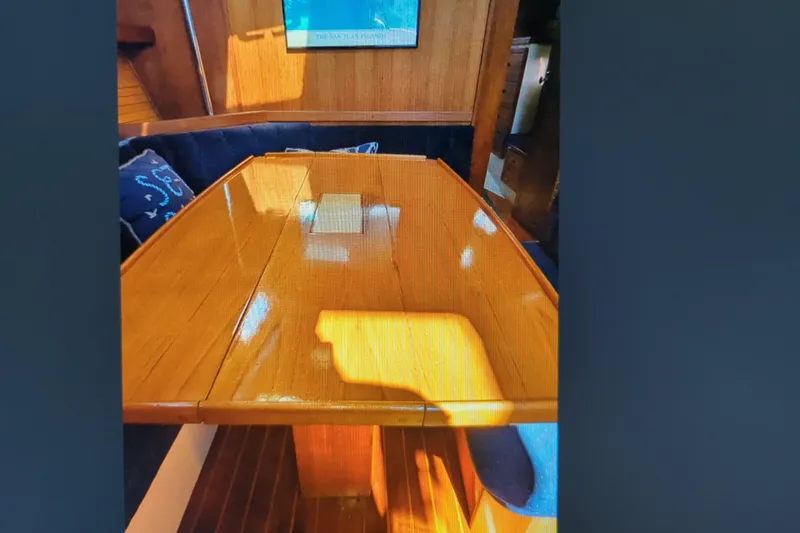 Slide: The Image of Interior of 1990 Catalina 42 sailboat with polished wooden table and cushioned seating. - 16