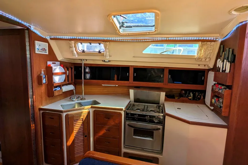 Slide: The Image of Interior of a 1990 Catalina 42 sailboat kitchen with stove, sink, and storage cabinets. - 17