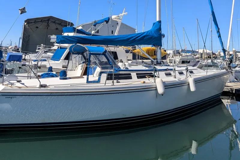 Slide: The Image of 1990 Catalina 42 sailboat docked in marina, featuring blue covers and sleek design. - 5