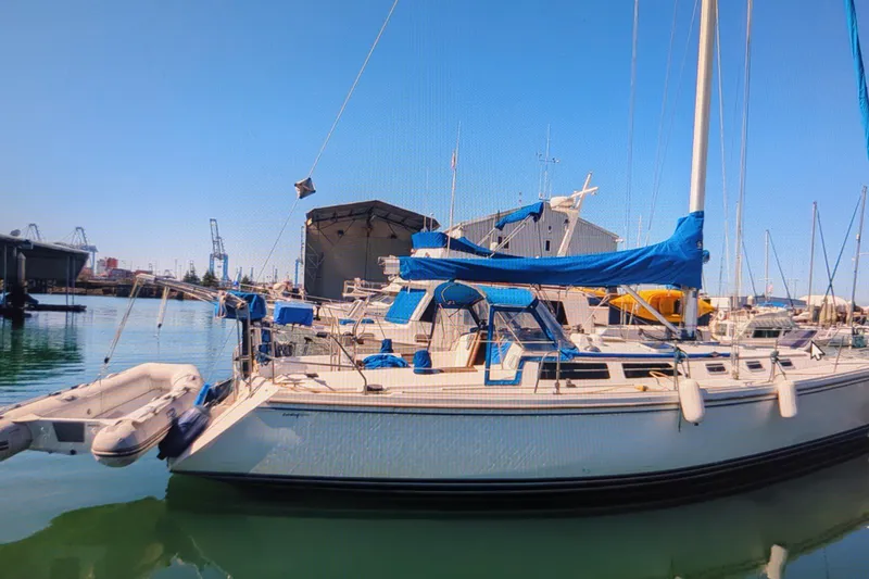 Slide: The Image of Sailboat Catalina 42, 1990 model, docked in a marina with blue covers and clear skies. - 6
