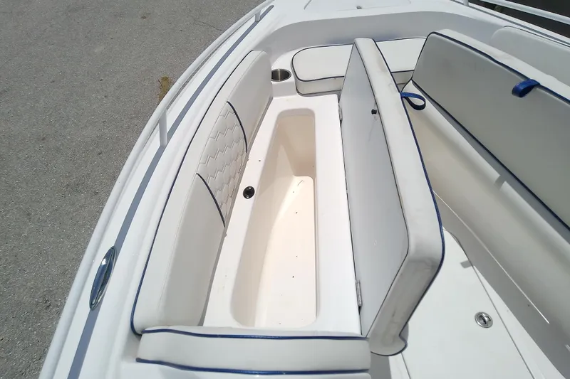 Slide: The Image of 2025 Glasstream 240 CCX boat interior seating with storage compartment, featuring white and blue upholstery. - 34