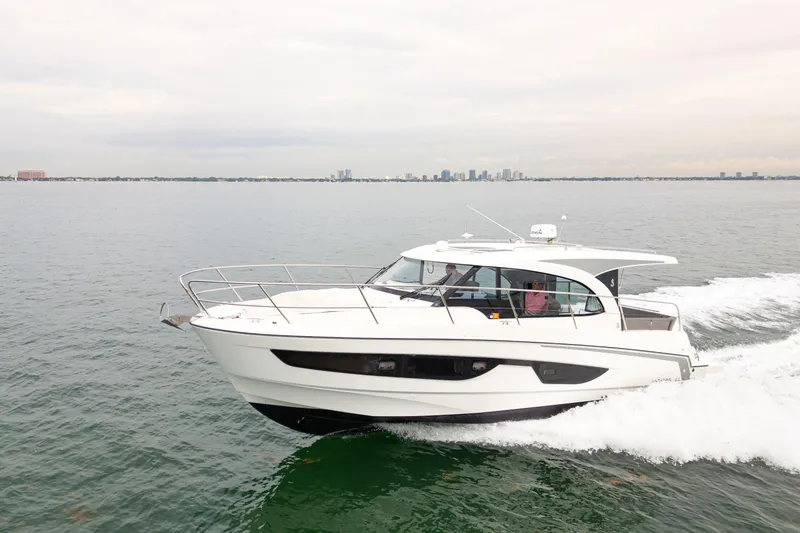 Slide: The Image of 2023 Beneteau Antares 11 cruising on open water with city skyline in background. - 14