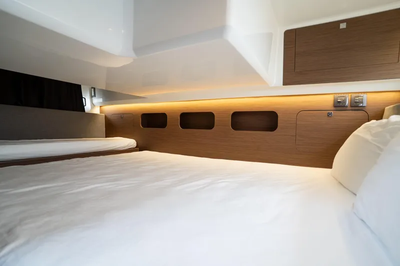 Slide: The Image of 2023 Beneteau Antares 11 cabin interior with modern wood finish and cozy bedding. - 31