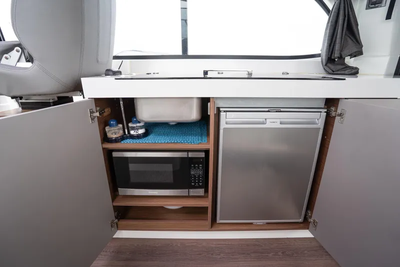 Slide: The Image of Interior of 2023 Beneteau Antares 11, featuring a compact kitchen with microwave and fridge. - 33