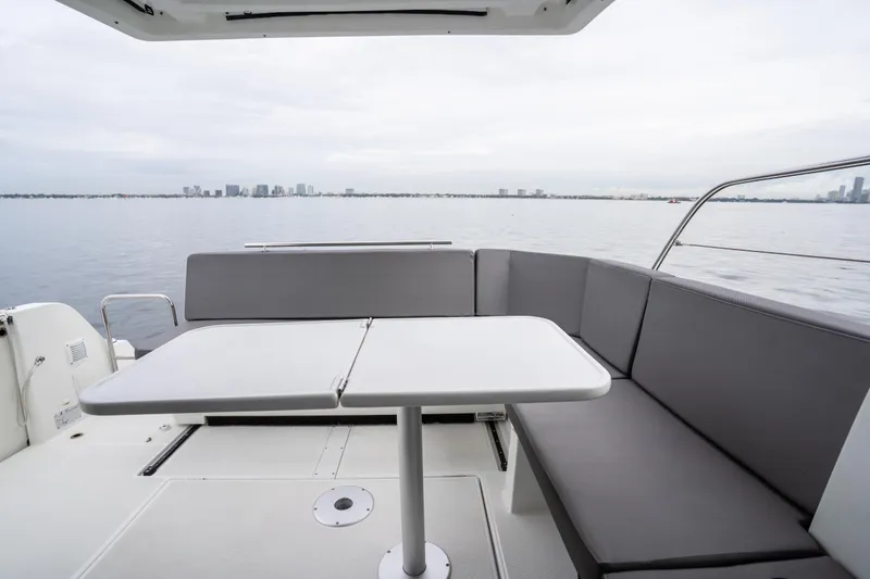 Slide: The Image of 2023 Beneteau Antares 11 boat deck with seating and table, overlooking calm waters. - 34