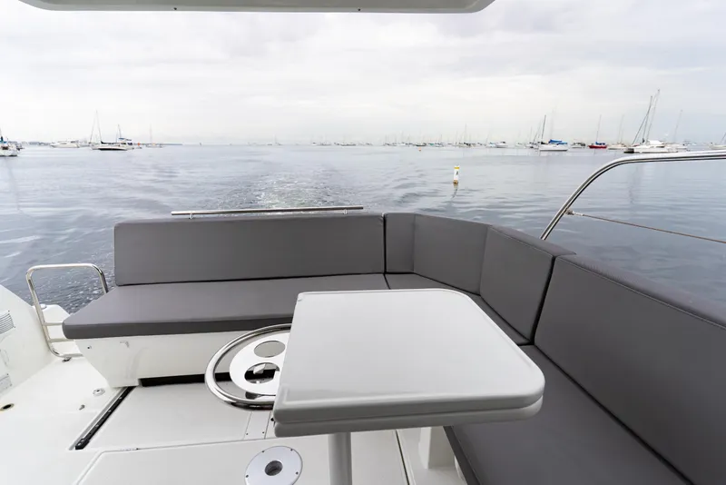 Slide: The Image of 2023 Beneteau Antares 11 boat deck with seating, overlooking calm waters and distant yachts. - 37