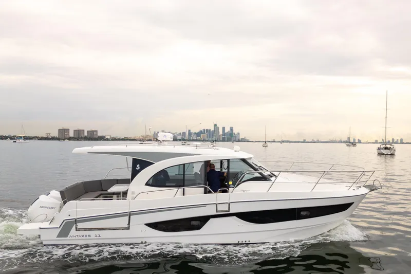 Slide: The Image of 2023 Beneteau Antares 11 cruising on calm waters with city skyline in background. - 7