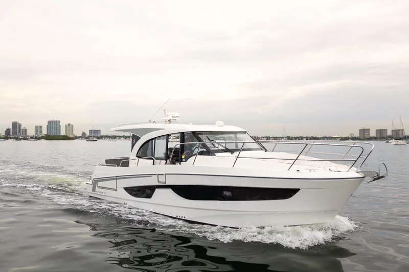 The Image of 2023 Beneteau Antares 11 cruising on water with city skyline in background. - 8