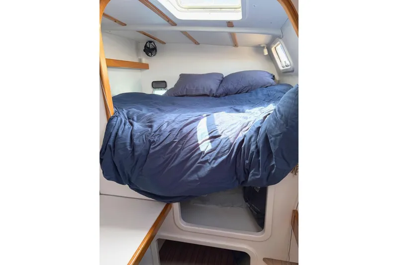 Slide: The Image of Cozy cabin bed in 2004 Outremer Standard yacht with blue bedding and natural light. - 13