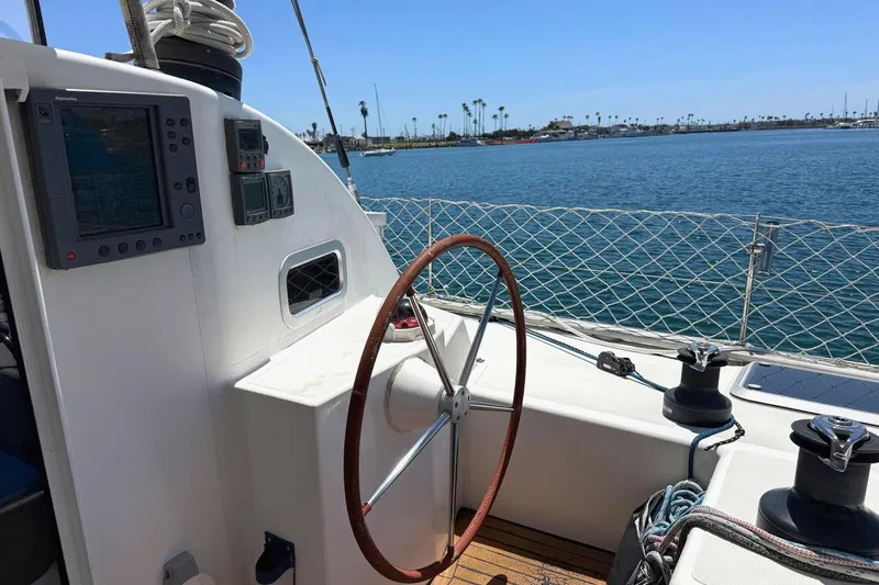 Slide: The Image of Steering wheel and controls on a 2004 Outremer Standard sailboat, overlooking calm waters. - 3