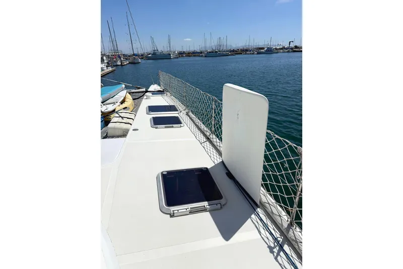 Slide: The Image of 2004 Outremer Standard catamaran deck with hatches, docked at marina under clear sky. - 4