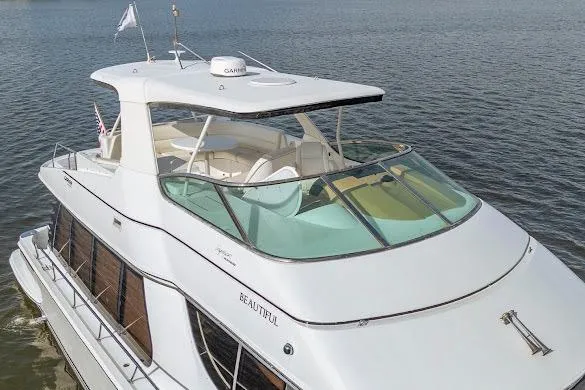 Slide: The Image of 2003 Carver 570 Voyager Pilothouse yacht on calm water, showcasing sleek design and spacious deck. - 14