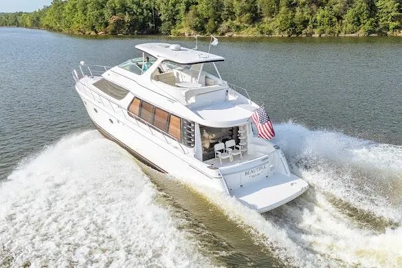 Slide: The Image of 2003 Carver 570 Voyager Pilothouse cruising on a scenic river with lush green trees. - 2
