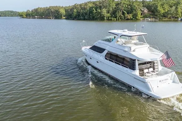 Slide: The Image of 2003 Carver 570 Voyager Pilothouse yacht cruising on a serene lake with lush greenery. - 8