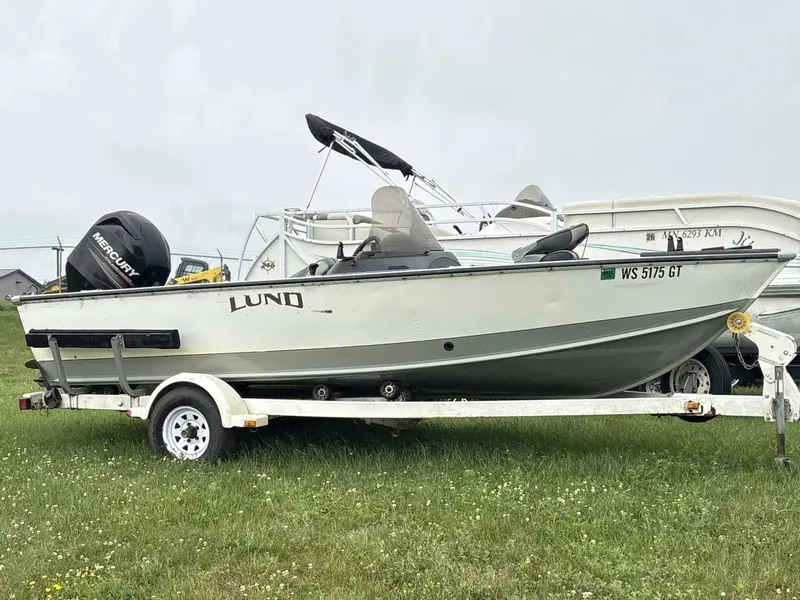 The Image of A white 2005 Lund 1700 EXP/SS boat on a trailer, parked on grass. - 1