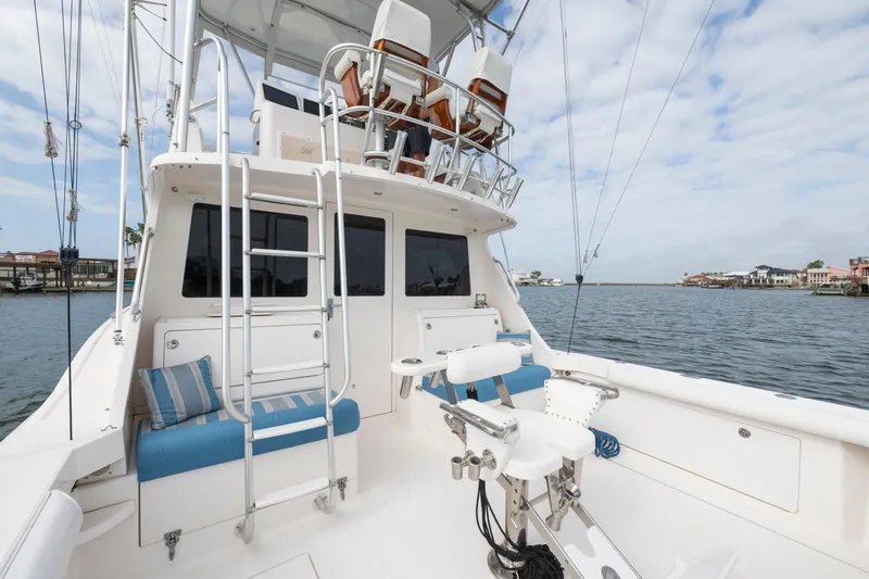 Slide: The Image of 2005 Cabo 35 Flybridge boat with fishing chair and ladder, docked by waterfront homes. - 12