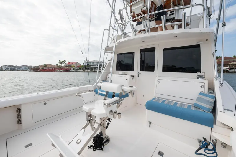 Slide: The Image of 2005 Cabo 35 Flybridge boat deck with seating and fishing chair, overlooking waterfront homes. - 13