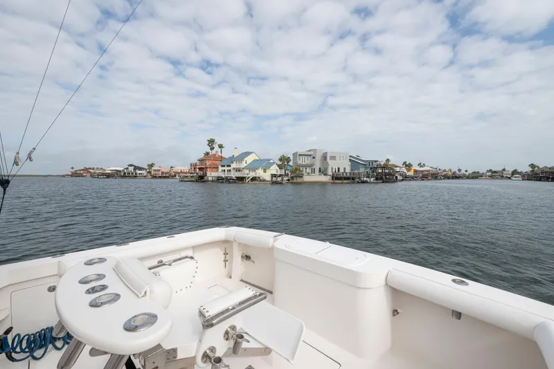Slide: The Image of 2005 Cabo 35 Flybridge boat overlooking waterfront homes under a cloudy sky. - 15