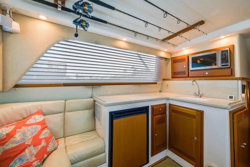 Slide: The Image of Luxurious 2005 Cabo 35 Flybridge interior with kitchenette, fishing rods, and cozy seating. - 18
