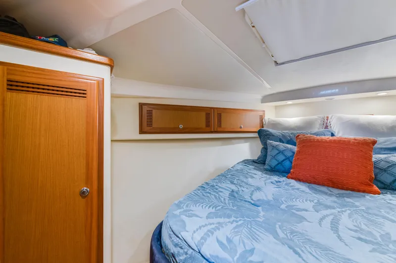 Slide: The Image of Cozy cabin interior of 2005 Cabo 35 Flybridge with blue bedding and wooden storage. - 22