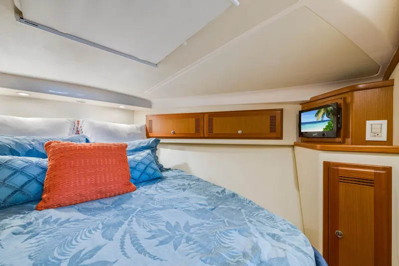 Slide: The Image of Cozy cabin interior of 2005 Cabo 35 Flybridge with blue bedding and small TV. - 23