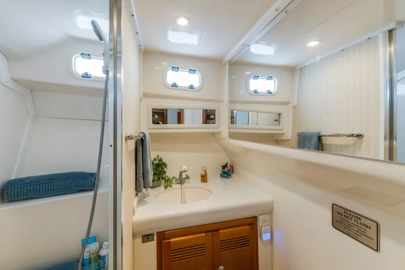 Slide: The Image of Bathroom interior of 2005 Cabo 35 Flybridge yacht, featuring sink, mirror, and storage. - 26