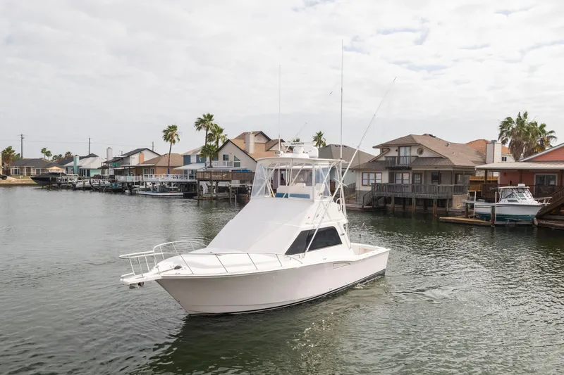 Slide: The Image of 2005 Cabo 35 Flybridge boat cruising near waterfront homes with palm trees. - 3
