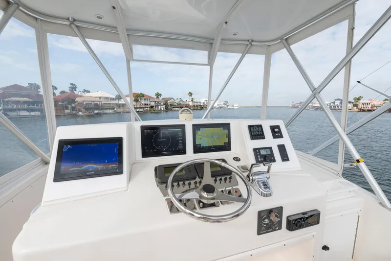 Slide: The Image of Helm of 2005 Cabo 35 Flybridge with navigation screens and steering wheel, overlooking waterfront homes. - 5