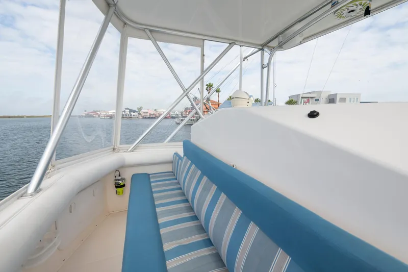 Slide: The Image of 2005 Cabo 35 Flybridge interior with striped seating, overlooking waterfront homes. - 8