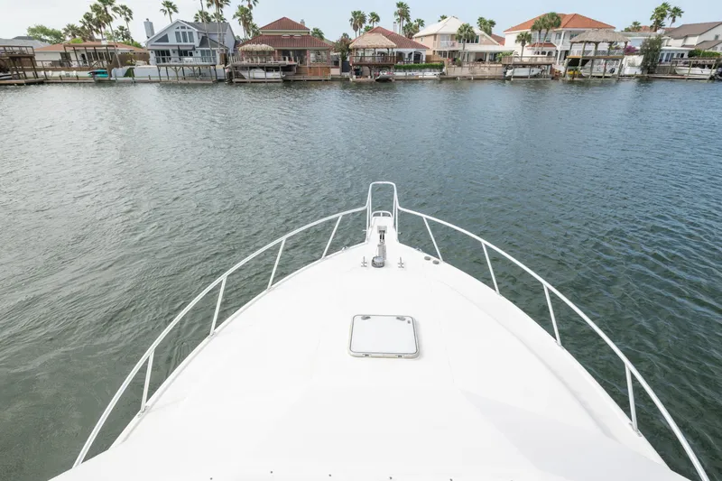 Slide: The Image of Bow view of 2005 Cabo 35 Flybridge yacht on calm water near waterfront homes. - 9
