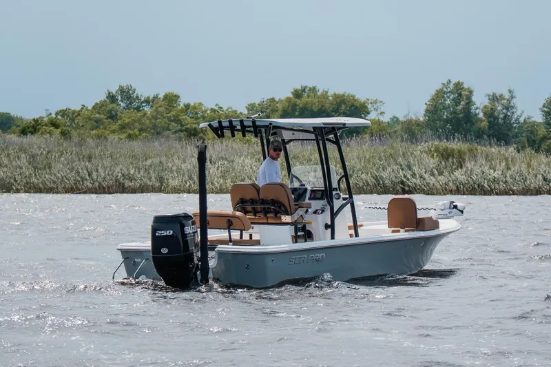 Slide: The Image of 2022 Sea Pro 228 Bay boat cruising on a lake with lush greenery in the background. - 12