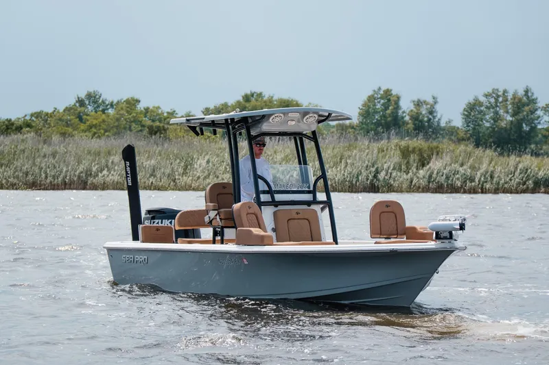 The Image of 2022 Sea Pro 228 Bay boat cruising on a calm river with lush greenery in the background. - 8