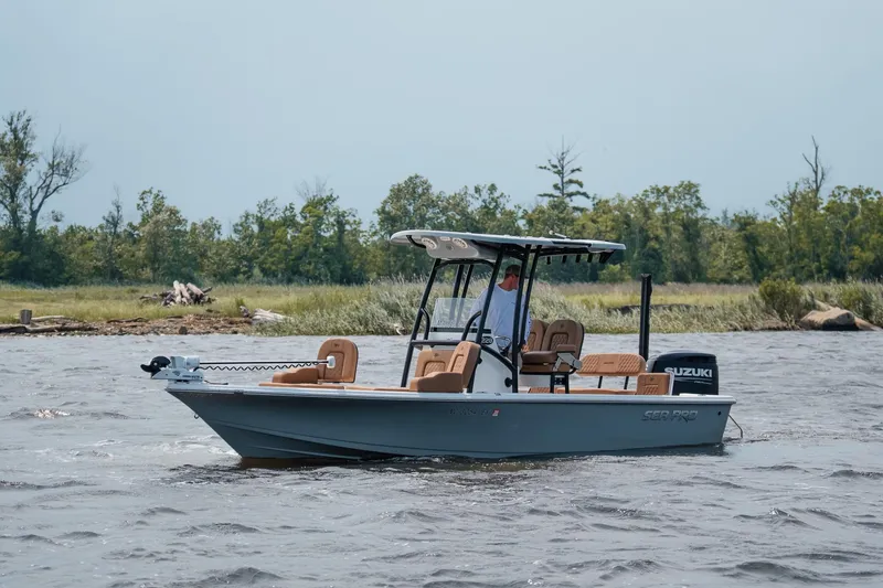 Slide: The Image of 2022 Sea Pro 228 Bay boat cruising on a lake with lush green shoreline. - 9