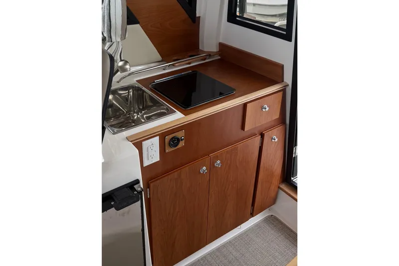 Slide: The Image of 2025 Cutwater C-248 Coupe interior kitchen with wooden cabinetry, sink, and stovetop. - 33