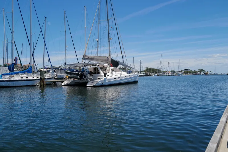 Slide: The Image of Sailboats docked at a marina, featuring a 2006 Leopard 43 catamaran under a clear blue sky. - 108